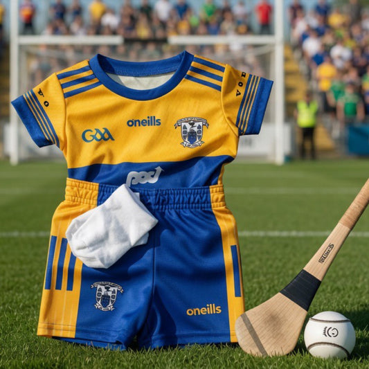 Children's GAA sports kit with blue and yellow colors on a grass field background.